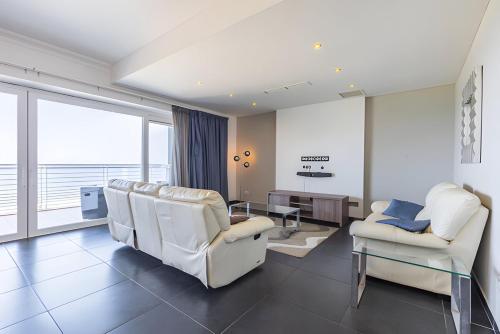 a living room with white chairs and a table at Luxury Coastal Apartment with Panoramic Views S9 in Sliema