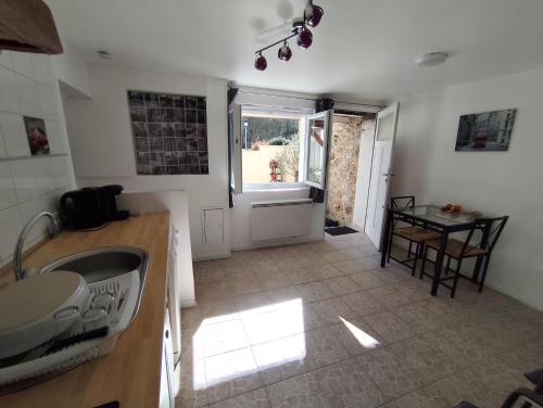 une cuisine avec un évier, une table et une fenêtre dans l'établissement Grand 2 pièces atypique aux portes de la Vallée de Chevreuse, à Châteaufort