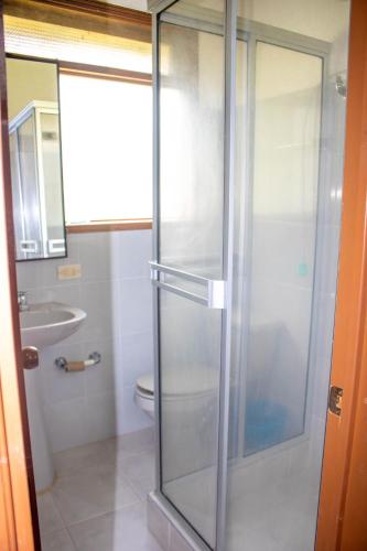 a bathroom with a glass shower with a toilet at Monteverde Best Inn - CASAS QUINTAS in Tenza