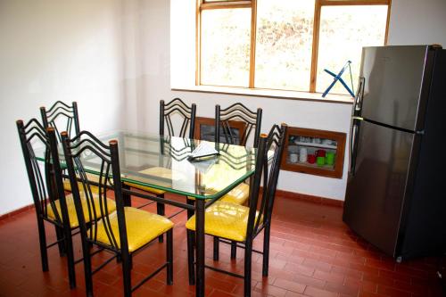 a dining room with a glass table with chairs and a refrigerator at Monteverde Best Inn - CASAS QUINTAS in Tenza