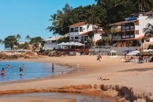 a beach with people in the water and buildings at Vila do Morro Pousada in Morro de São Paulo