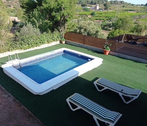 a swimming pool with two chairs on a lawn at Chalet con piscina privada in Borriol
