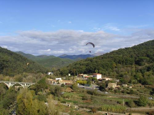 a person flying a kite over a town with a bridge at Cala Clareta in Castellfollit de la Roca
