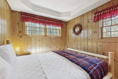 a bedroom with wooden walls and a bed with white sheets at Stone Lake View in Manitowish Waters