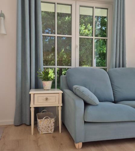 a blue couch in a room with a table and a window at Káli Pillangó - Ház a völgyben in Balatonhenye