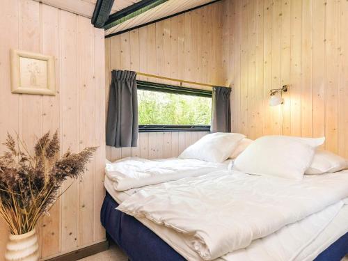 a bed in a room with wooden walls and a window at 6 person holiday home in Væggerløse-By Traum in Marielyst