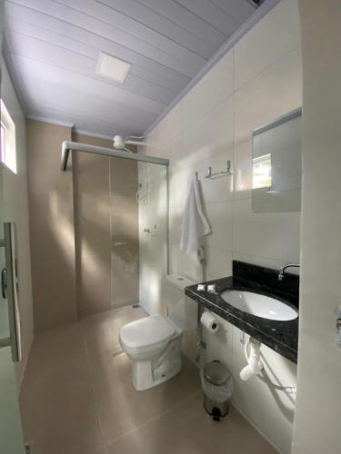 a white bathroom with a toilet and a sink at Executive Hotel Aguas lindas GO in Macacos