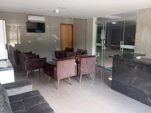 a lobby with a bunch of chairs and a television at Executive Hotel Aguas lindas GO in Macacos