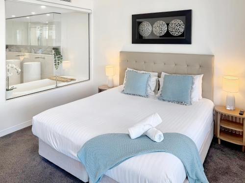 a bedroom with a large white bed with blue pillows at Oracle 11th floor Tower 1 - GC Getaways in Gold Coast