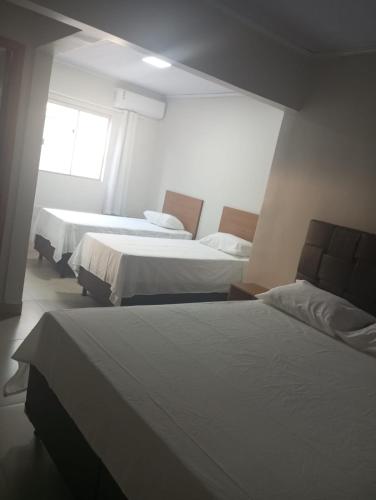 a hotel room with two beds and a window at Executive Hotel Aguas lindas GO in Macacos
