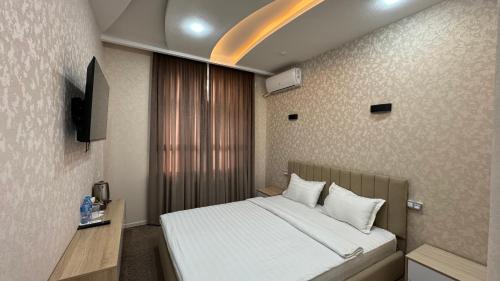 a hotel room with a bed and a television at Chinor Hotel Fergana in Fergana