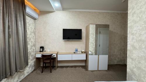 a room with a desk and a television on the wall at Chinor Hotel Fergana in Fergana