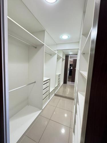 a walk in closet with white cabinets and a mirror at Suites Premium 2 quartos in João Pessoa