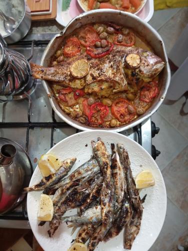 two pans of fish on plates on a stove at Skb Sea House Taghazout in Taghazout