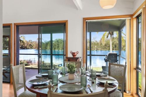 a dining room with a table and views of the water at Evergreen Escape in Dora Creek