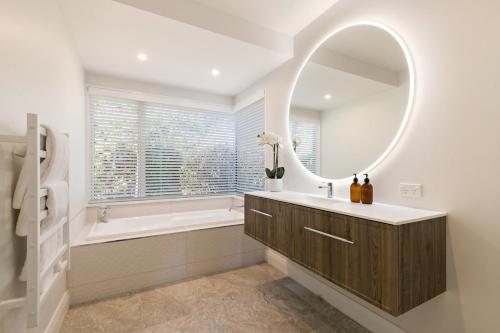 a bathroom with a tub and a sink and a mirror at Baywaters Retreat by Sothebys Luxury Rental Homes in Closeburn