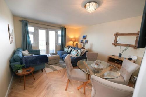a living room with a blue couch and a glass table at Caledonia by the Sea in Saltcoats