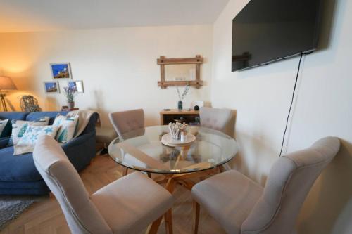 a living room with a glass table and chairs at Caledonia by the Sea in Saltcoats