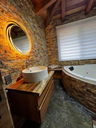 a bathroom with a sink and a tub and a mirror at Cabaña Arelys in Cedro