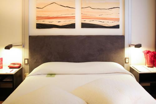 a bedroom with a white bed with a painting above it at Art Hotel Museo in Prato
