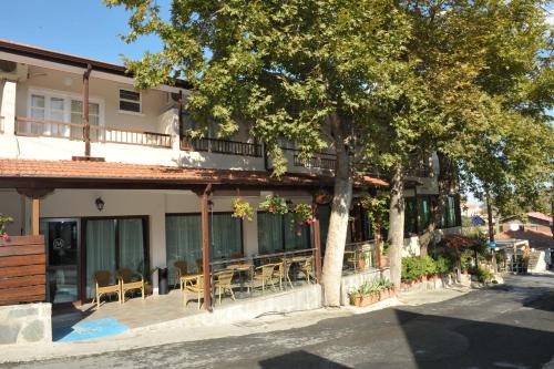 a building with chairs and a tree in front of it at Minaides Hotel in Kakopetria