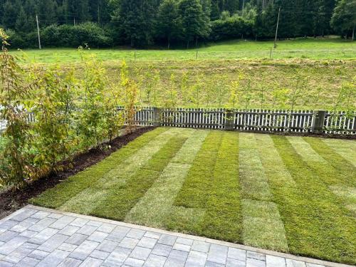 a garden with a wooden fence and grass at Obermöschach 5A in Obermöschach