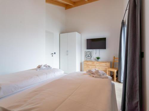 a white bedroom with two beds and a tv at Obermöschach 5A in Obermöschach