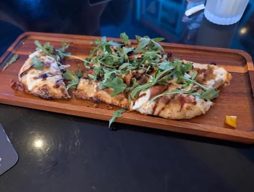 a pizza on a wooden plate on a table at Brush Inn and Suites in Brush