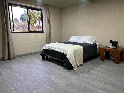 a bedroom with a bed and a window and a table at Bosque escondido in Valle de Bravo
