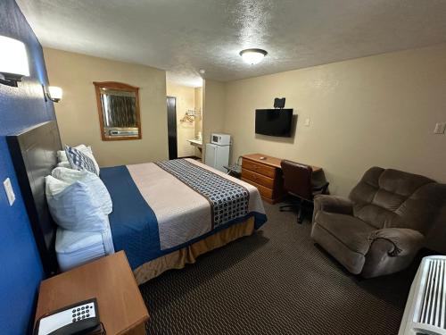 a hotel room with a bed and a chair and a desk at Eco-Lux Inn Norfolk in Norfolk