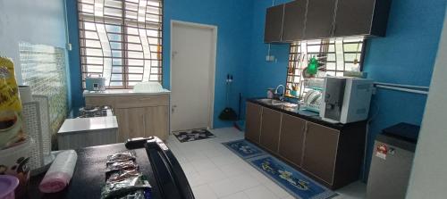 a kitchen with blue walls and a counter with a microwave at HOMESTAY DAWAMI KUALA Kedah, KEDAH in Kuala Kedah
