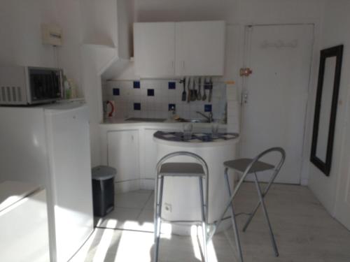 - une cuisine blanche avec 2 chaises et un évier dans l'établissement Les Floralies, à Juan-les-Pins