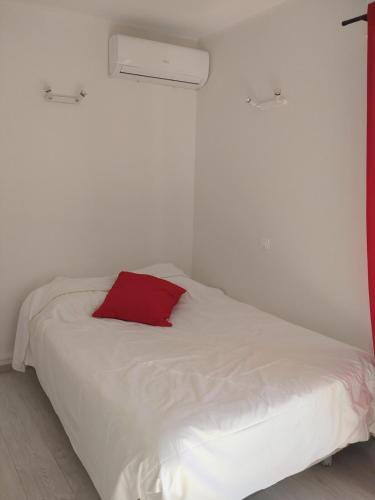 - un lit blanc avec un oreiller rouge dans l'établissement Les Floralies, à Juan-les-Pins