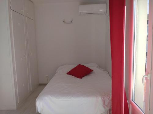 - une petite chambre avec un oreiller rouge sur un lit dans l'établissement Les Floralies, à Juan-les-Pins