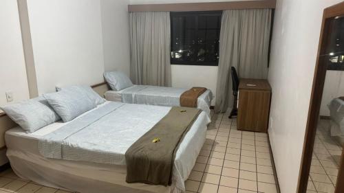 a hotel room with two beds and a window at Apart no Centro Turístico in Manaus