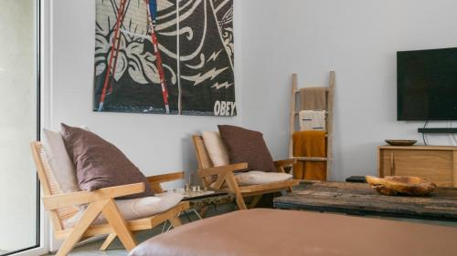 a living room with chairs and a table and a tv at Desert Serenity Gateway To Joshua Tree in Joshua Tree