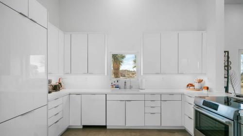 a white kitchen with white cabinets and a window at Desert Serenity Gateway To Joshua Tree in Joshua Tree