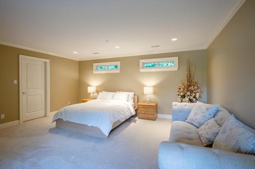 a bedroom with a bed and a couch and two windows at Luxury 5BR Villa, Gym, Theater & Ocean Views in West Vancouver