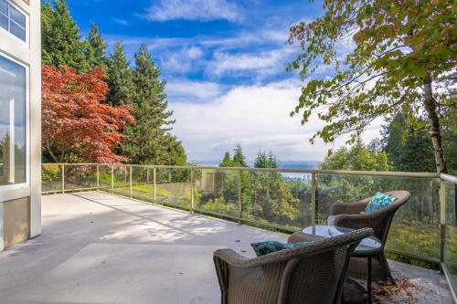 a patio with chairs and a table on a balcony at Luxury 5BR Villa, Gym, Theater & Ocean Views in West Vancouver