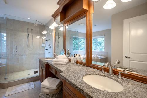 a bathroom with a sink and a shower and a mirror at Luxury 5BR Villa, Gym, Theater & Ocean Views in West Vancouver