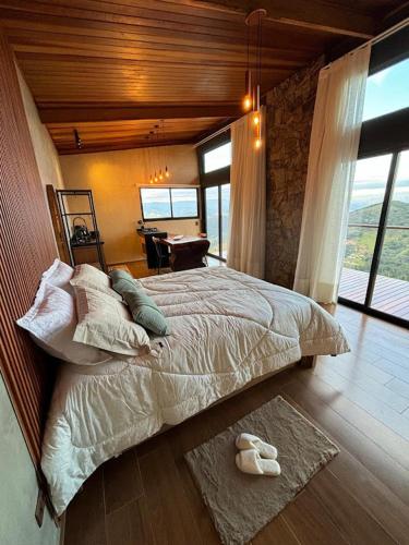 a bedroom with a large bed and a table at Chalé Manacá in Sapucaí-Mirim