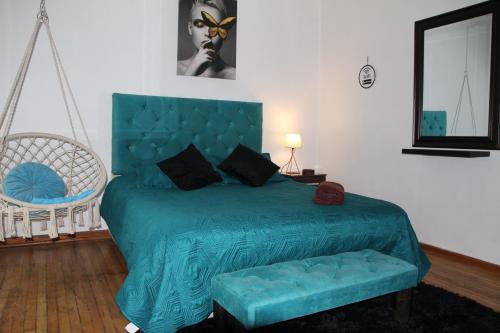 a bedroom with a bed with a blue bedspread and a chair at Hostal Sueños De Lujo in Talca