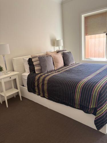 a bedroom with a bed with a striped blanket and a window at Private, Central, Sunny Guest Room in Welcoming Home in Campbelltown
