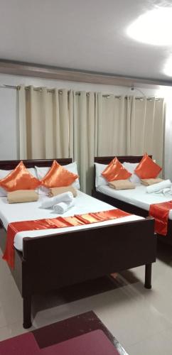BariliにあるPacifico's Hostelのオレンジ枕付きのベッド2台が備わる客室です。