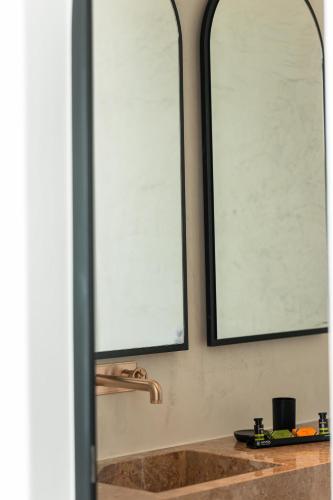 two mirrors above a sink in a bathroom at Muse οf Mykonos Luxury Suites in Mýkonos City