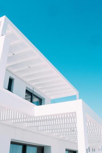 a white building with a blue sky in the background at Muse οf Mykonos Luxury Suites in Mýkonos City
