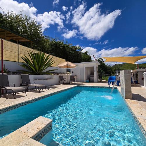 a pool with chairs and umbrellas next to a house at Casa Colora in Naguabo