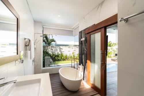 スミニャックにあるThe Daha Luxury Villasのバスルーム(バスタブ付)、大きな窓が備わります。