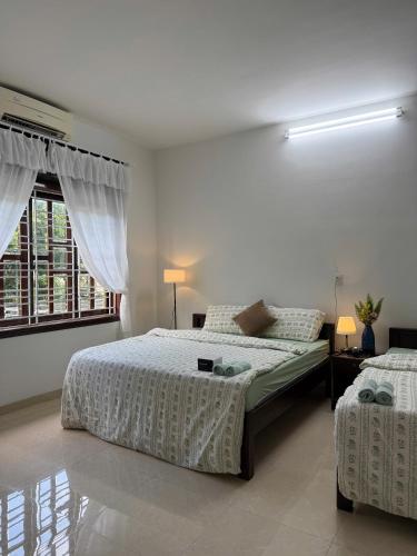a white bedroom with two beds and a window at Green homestay, King beds, 5min from Hue city in Thôn Trường Giang