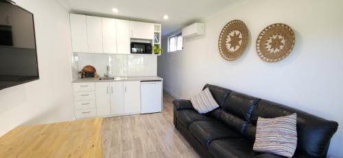 a living room with a black leather couch and a kitchen at Seaside Aura in Victor Harbor